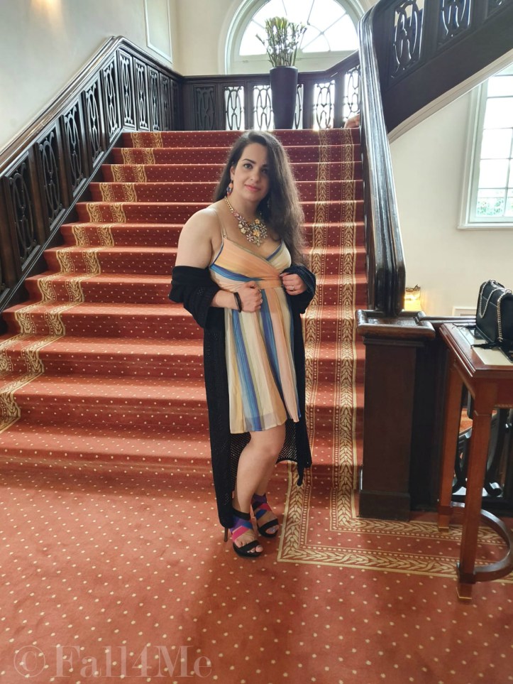 A dress with the colors of the sky under a black summer knit-cardigan and with a fringed bag.