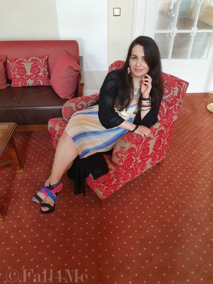 A dress with the colors of the sky under a black summer knit-cardigan and with a fringed bag.