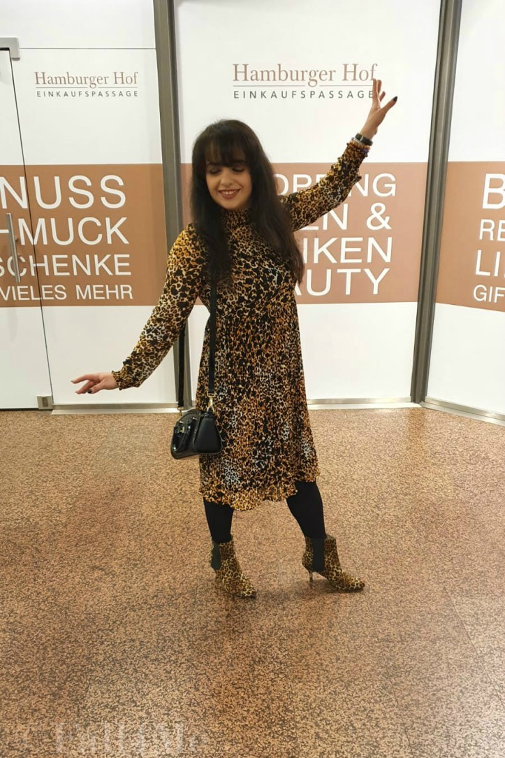 A leo-print dress styled with corresponding ankle boots and black accessories.