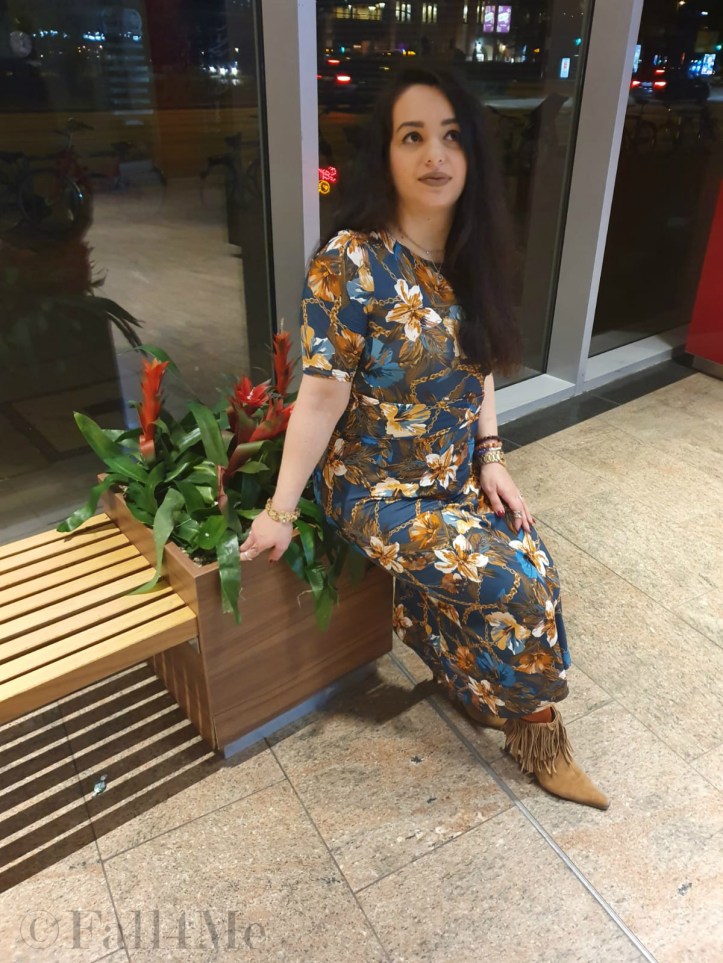 A turquoise dress with flowers in shades of cognac and golden accessories.