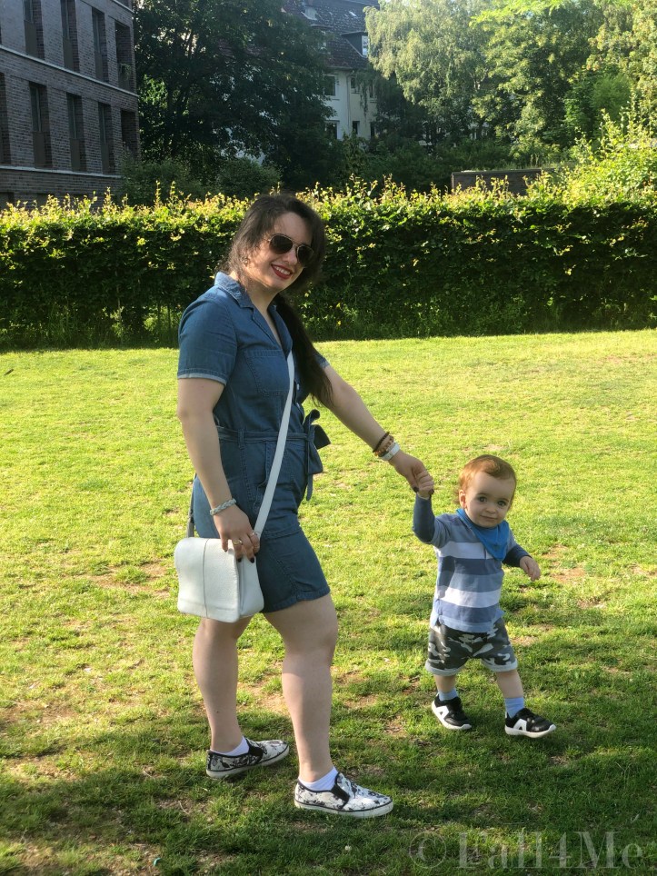 A denim jumpsuit combined with white leather accessories, silver jewellery and a red lipstick.