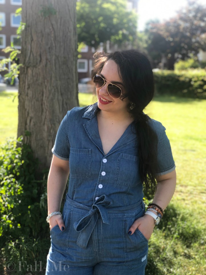 A denim jumpsuit combined with white leather accessories, silver jewellery and a red lipstick.