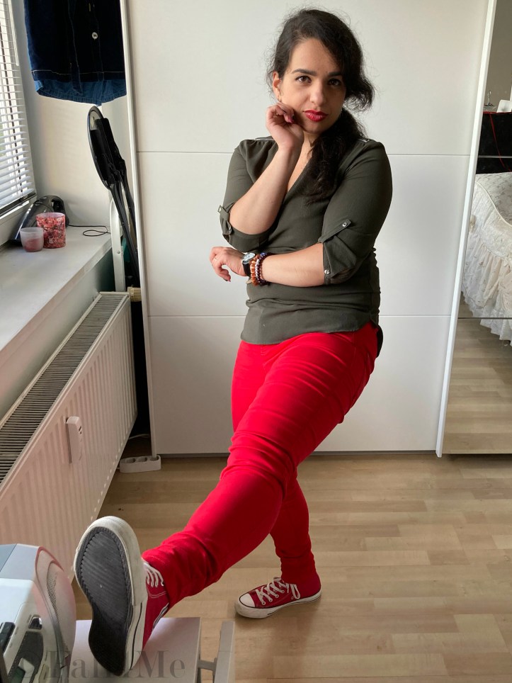 An olive green blouse combined with red lipstick and red skinny jeans and red chucks.