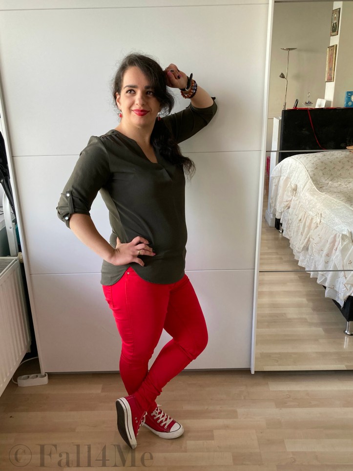An olive green blouse combined with red lipstick and red skinny jeans and red chucks.
