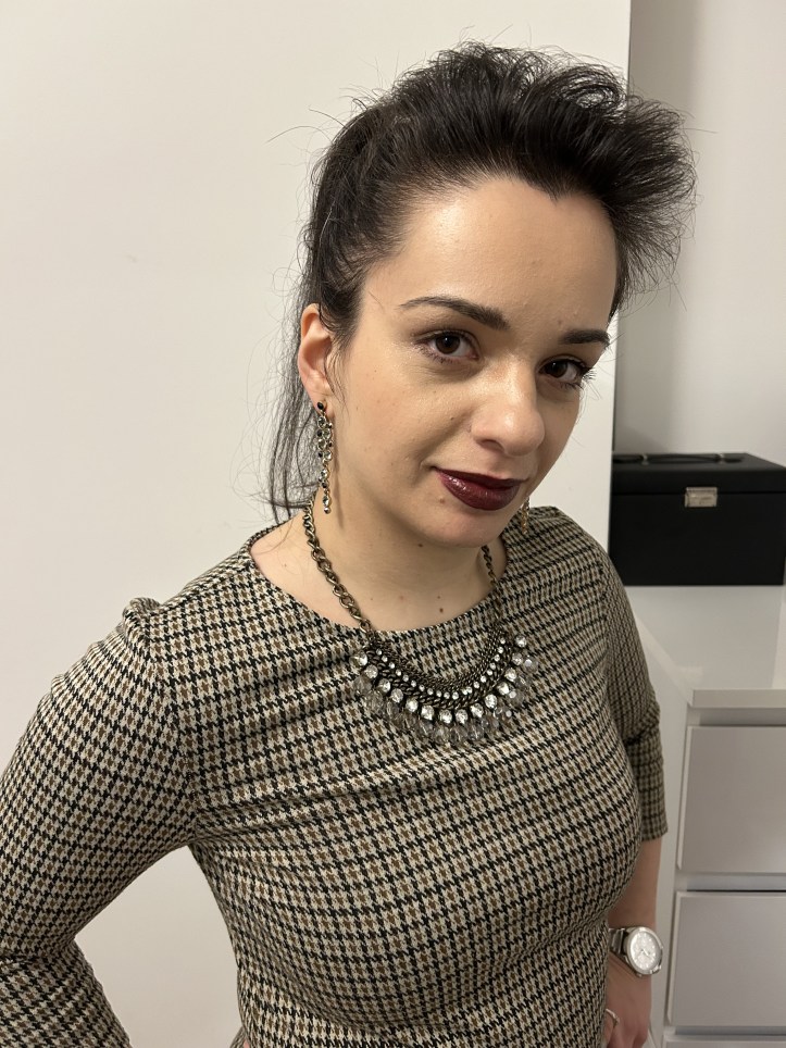 An outfit in corprate core pattern, figure hugging faux-leather leggings in dark green and overknees.