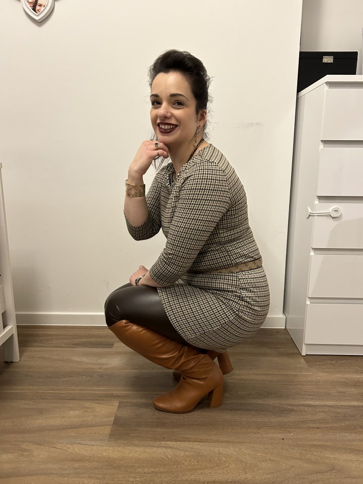 An outfit in corprate core pattern, figure hugging faux-leather leggings in dark green and overknees.