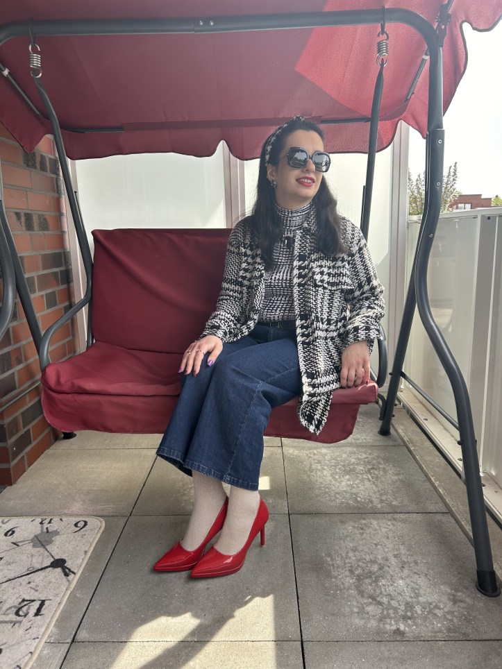 Oversized checked bouclé coat with jeans and red pumps.