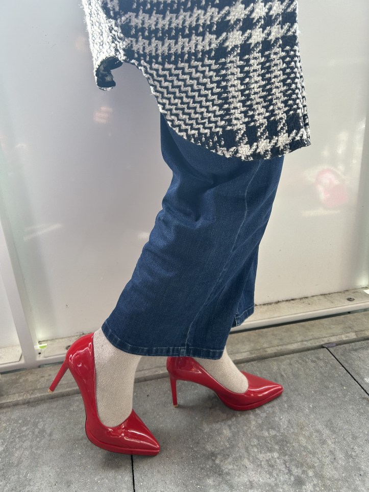 Oversized checked bouclé coat with jeans and red pumps.