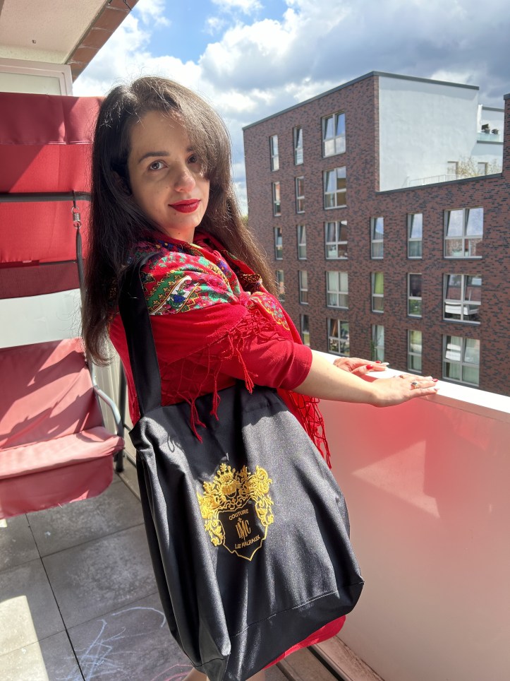 A red dress with a big ribbon worn with the accessory of the month a traditional Slavic/Baltic floral scarf, flats and a tote bag.