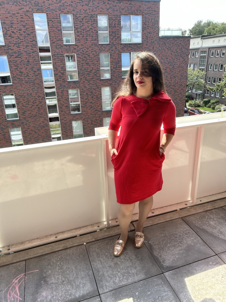 A red dress with a big ribbon worn with the accessory of the month a traditional Slavic/Baltic floral scarf, flats and a tote bag.