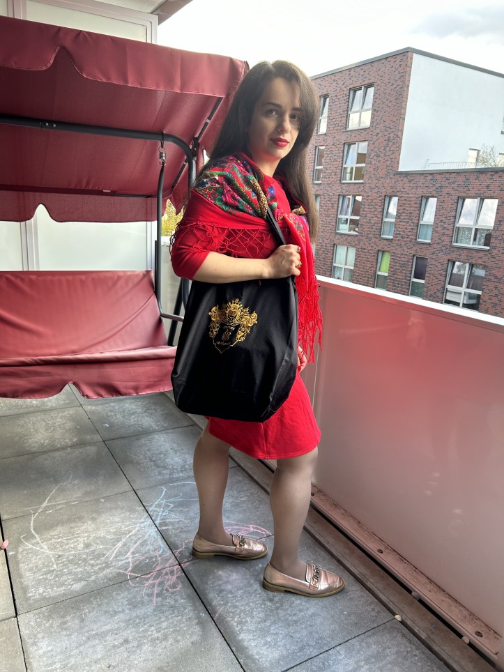 A red dress with a big ribbon worn with the accessory of the month a traditional Slavic/Baltic floral scarf, flats and a tote bag.