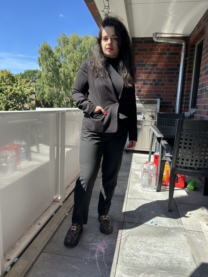 Reduction seduction with a suit all in black with natural curls.