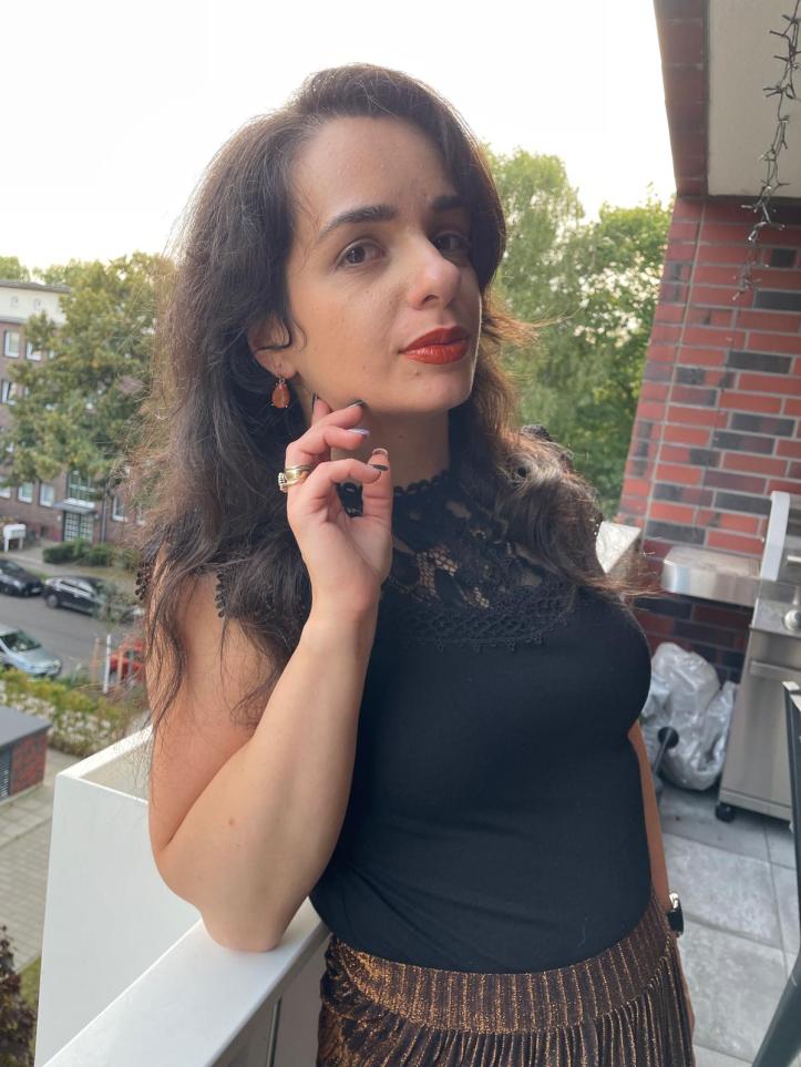 A gold-glitter pleated skirt worn with a black shirt and black/brown loafers